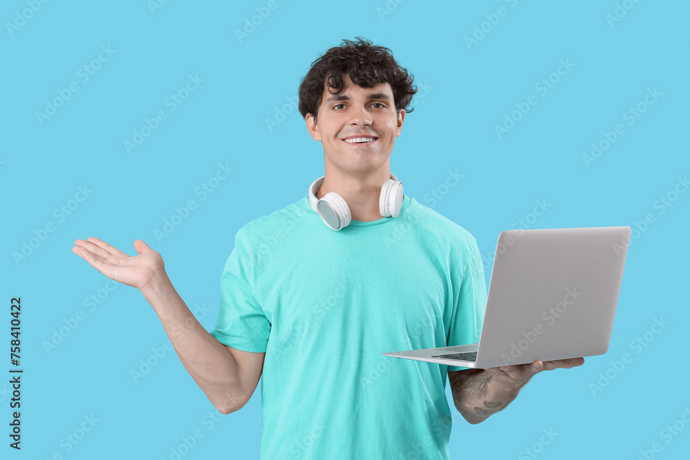 Male programmer with laptop showing something on blue background Male programmer with laptop showing something on blue background