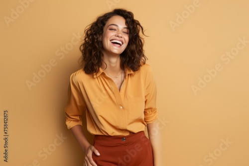 Cheerful young woman laughing and looking away while standing against yellow background
