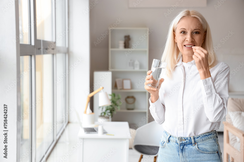 Mature woman with glass of water taking pills at home Mature woman with glass of water taking pills at home