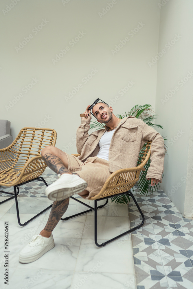 Hombre joven tatuado y fitness posando en la entrada y hall del hotel donde viaja con ropa urbana moderna Hombre joven tatuado y fitness posando en la entrada y hall del hotel donde viaja con ropa urbana moderna