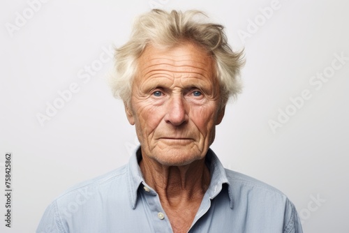 Portrait of a senior man looking at the camera over grey background © Igor