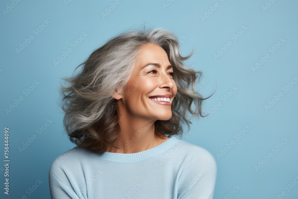 smiling senior woman with long grey hair looking up on blue background smiling senior woman with long grey hair looking up on blue background