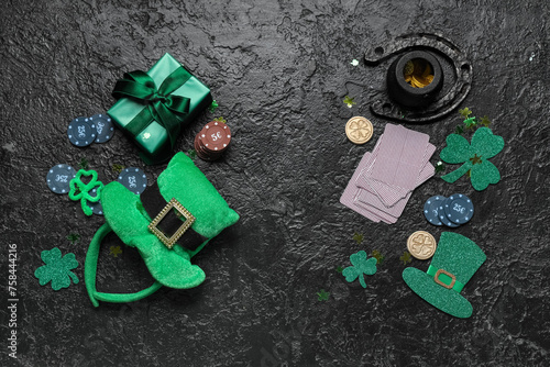 Poker chips, gift box, cards and decorations for St. Patrick's Day celebration on black grunge background