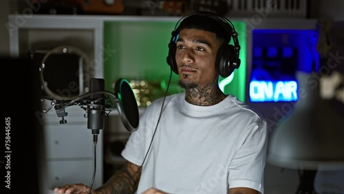 Young latin man musician listening to music singing song at music studio