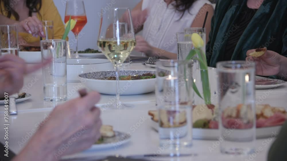 Shallow depth of field shot of glasses of wine and water and plates with food on a dinner table with people around it. Shallow depth of field shot of glasses of wine and water and plates with food on a dinner table with people around it.