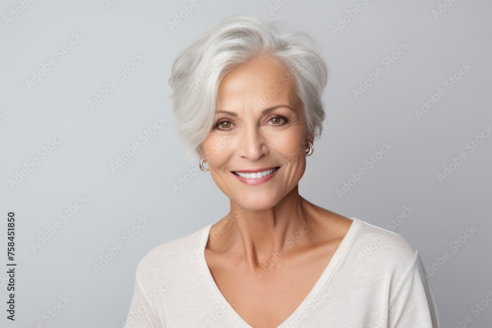 Portrait of smiling senior woman looking at camera over grey background.
