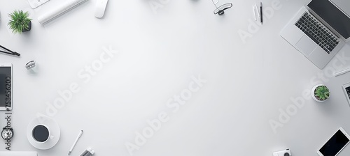 Minimalist white desk with potted plant, coffee cup, and neatly arranged office supplies photo