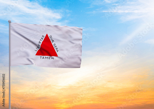 3D illustration of a Minas Gerais flag extended on a flagpole and in the background a beautiful sky with a sunset photo