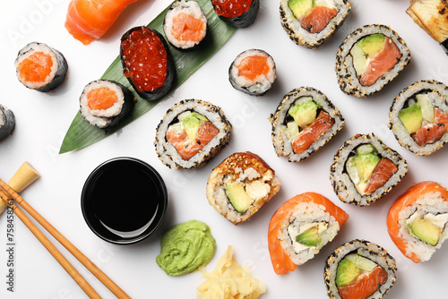 Set of delicious sushi rolls on white background, flat lay