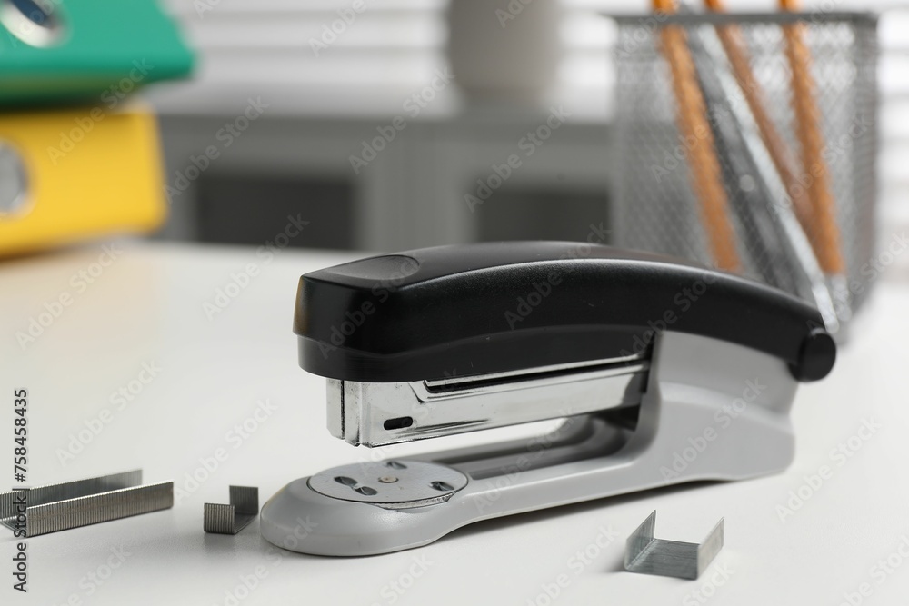 Stapler and metal staples on white table indoors, closeup Stapler and metal staples on white table indoors, closeup
