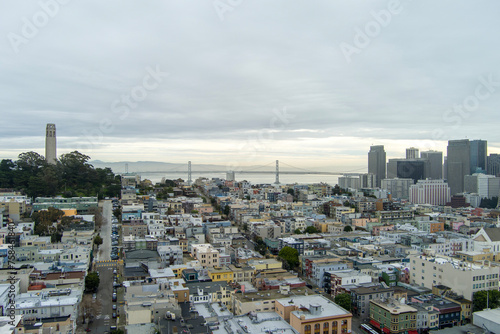 aerial shot of skyscrapers, hotels and office buildings in the city skyline and the bay bridge over the ocean water, Coit Tower, apartments and cars on the street in San Francisco California USA