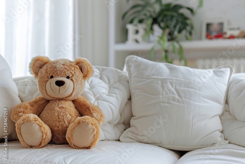 Plush teddy bear sitting on white couch with pillows