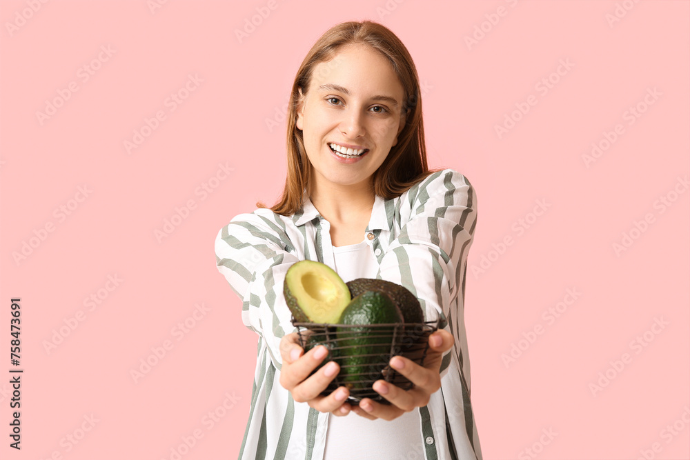 Pretty young woman with basket of avocados on pink background Pretty young woman with basket of avocados on pink background