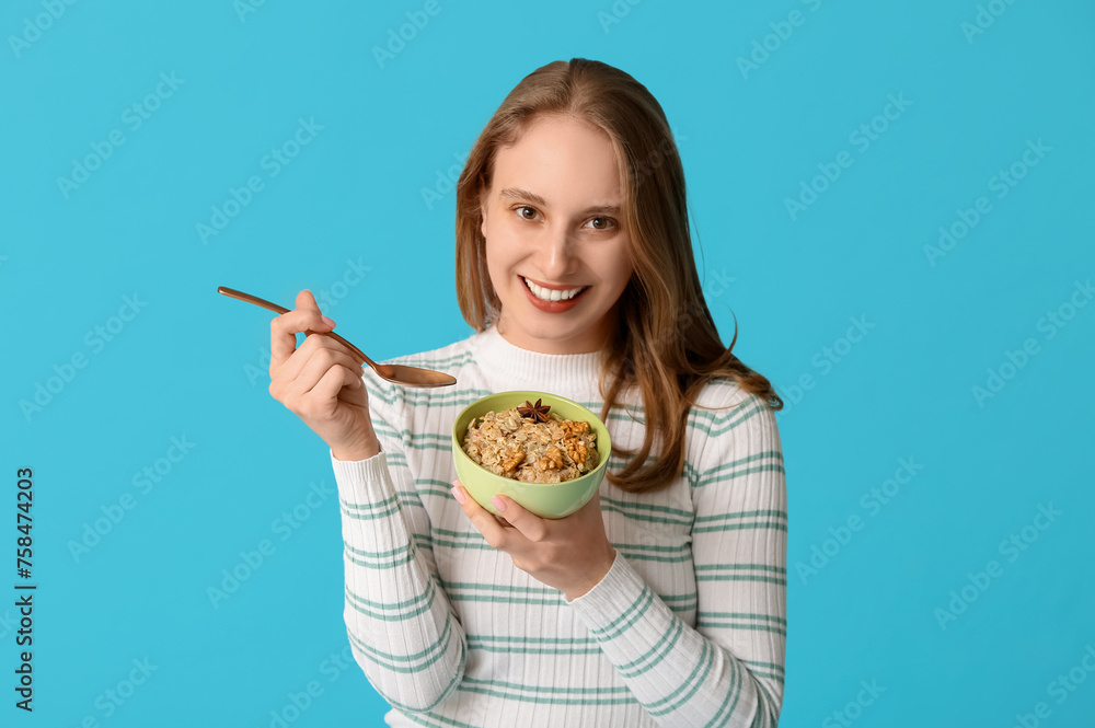 Happy young woman with bowl of healthy oatmeal on blue background Happy young woman with bowl of healthy oatmeal on blue background