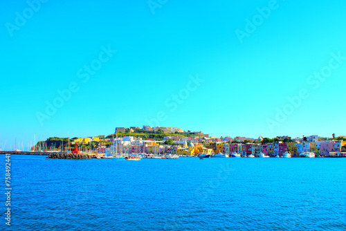 Colorful view at Isola di Procida in the Gulf of Naples on the Tyrrhenian Sea with the pastel buildings of Via Roma, the ships and ferries connecting with Napoli and other places, docked and waiting