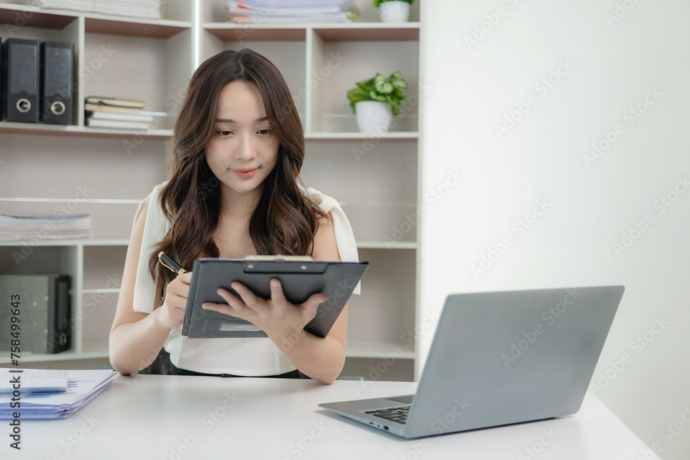 Asian female accountant working on laptop and doing paperwork, tax, trading, and financial consulting and accounting analysis investment information report Financial concepts and tax system Asian female accountant working on laptop and doing paperwork, tax, trading, and financial consulting and accounting analysis investment information report Financial concepts and tax system