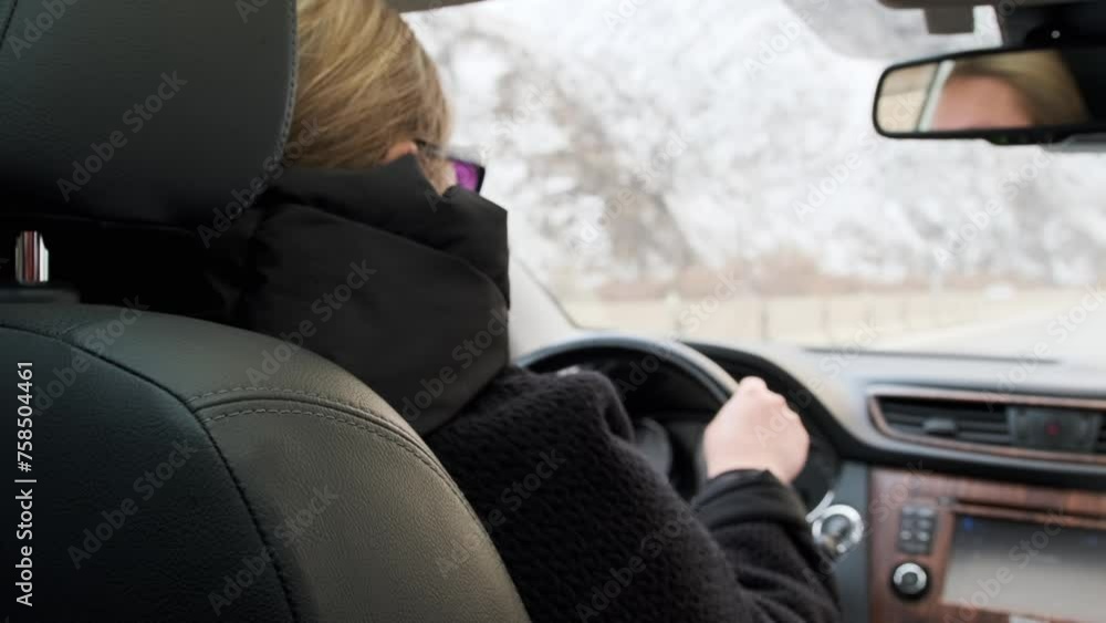 Female driver behind the wheel road highway track. Adult woman drives car along deserted road with snow-covered hills. Driving transport concept. Female driver behind the wheel road highway track. Adult woman drives car along deserted road with snow-covered hills. Driving transport concept.