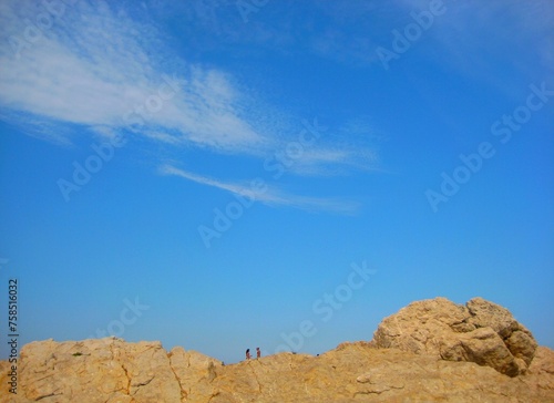 Two people on the rocks of cliffs landscape with blue sky background