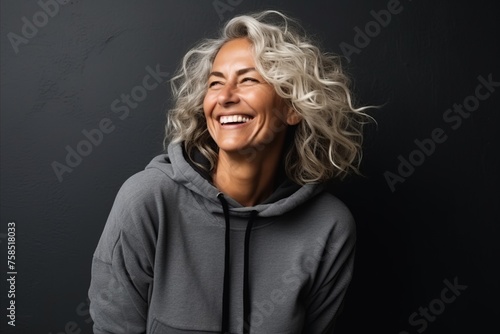 Portrait of a beautiful middle aged woman laughing against a dark background © Igor