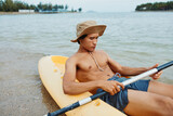 Happy Asian man kayaking on a tropical beach vacation, enjoying the summer sun and vibrant nature