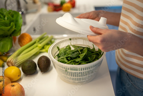Preparing of useful, fresh, healthy vegan home dinner, snack of fruit and vegetables. Drying of greens spinach in plastic hand food centrifuge. Natural ingredients full of vitamins for detox, slimming photo