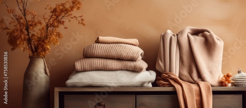 A hardwood dresser with a vase of dried flowers and a pile of clothes on top, creating a beautiful still life photography scene in a peachthemed room photo