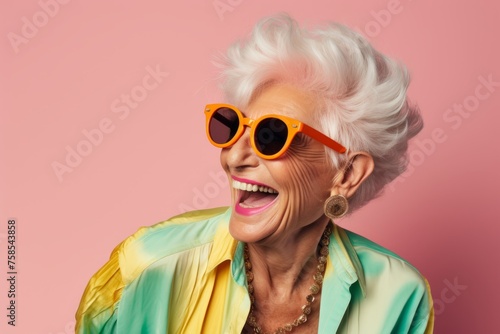 Portrait of a happy senior woman in sunglasses. Isolated on pink background.