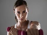 Serious woman, portrait and fitness with dumbbells for weightlifting, workout or exercise on a gray studio background. Female person, bodybuilder or athlete with small barbells for training on mockup
