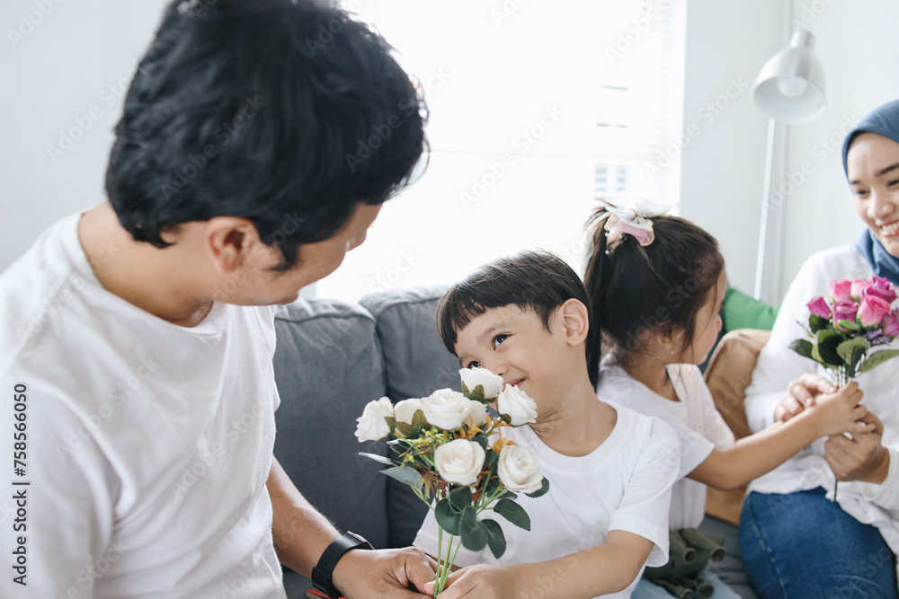 Kids giving flowers to their parents. Family bonding time in living room. Kids giving flowers to their parents. Family bonding time in living room.