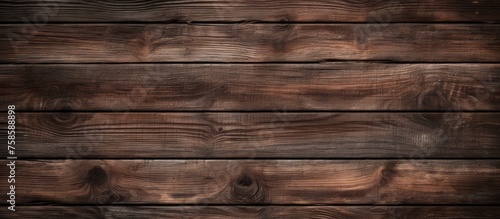 A closeup of a brown hardwood table with a wood stain pattern, made of rectangular planks of plywood. The blurred background enhances the focus on the table