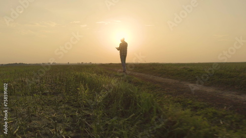 The figure of a farmer in the rays of the setting sun. Sunset in an agricultural field on which a farmer walks.