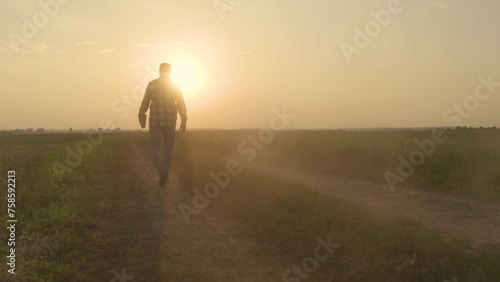 The figure of a farmer in the rays of the setting sun. Sunset in an agricultural field on which a farmer walks.