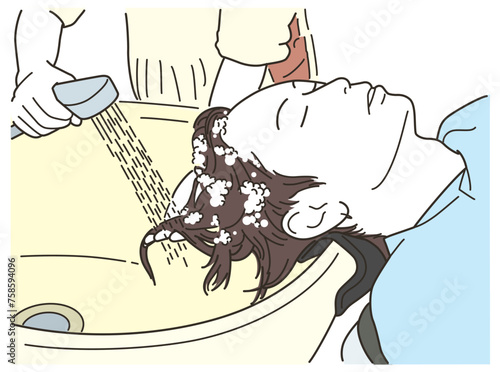 美容室のシャンプー台で仰向けでシャンプーをしてもらう若い男性