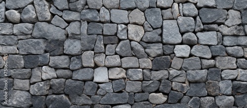 A detailed view of a grey stone wall showcasing the intricate pattern of the brickwork. The natural building material of bedrock creates a sturdy and durable structure photo