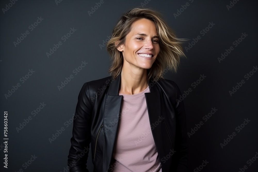 Portrait of a beautiful young woman in a leather jacket on a dark background Portrait of a beautiful young woman in a leather jacket on a dark background