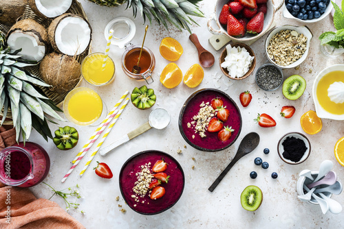 Preparing acai bowl in flat lay style with tropical fruits and grains photo