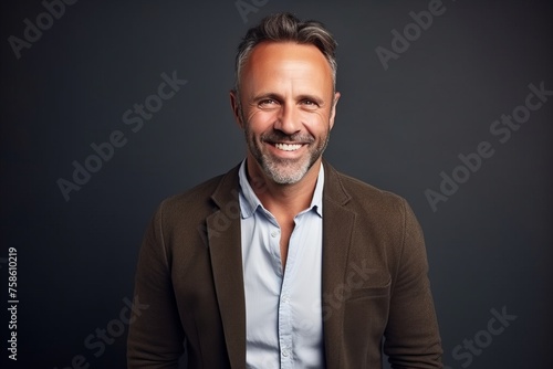 Portrait of a handsome middle-aged man smiling against a dark background.