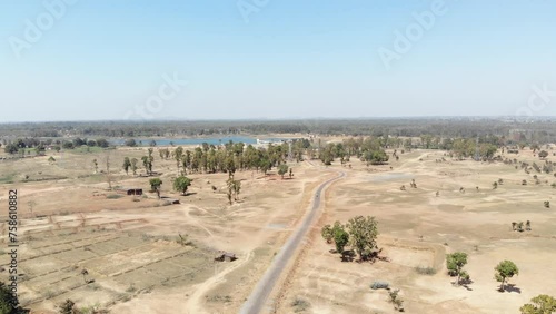 Wide aerial shot of barren arid land with asphalt road and water at a distance in Charu village in Chatra, Jharkhand, India. photo