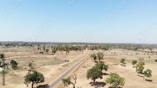 Backward aerial shot of barren arid land with asphalt road and water at a distance in Charu village in Chatra, Jharkhand, India. photo