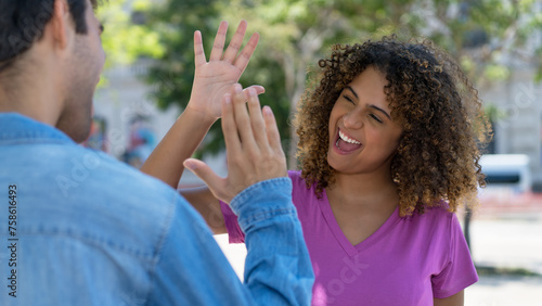 Laughing latin american female young adult giving high five to hispanic friend