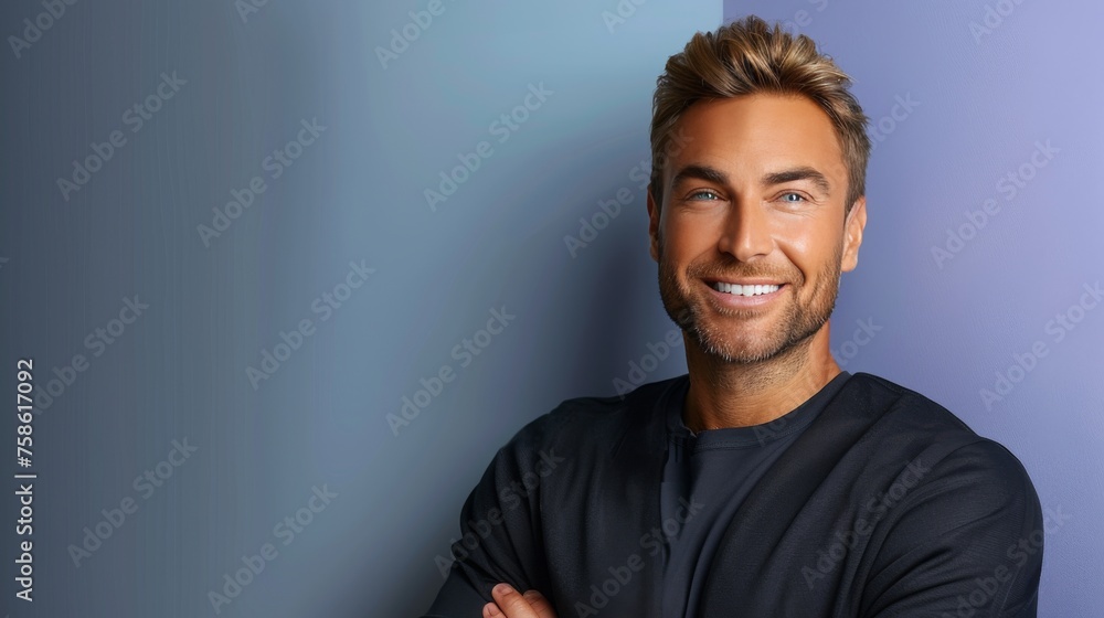 Fototapeta premium A man with a beard and a smile is standing in front of a blue wall