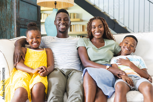 A cheerful African American family is sitting closely on a sofa at home photo