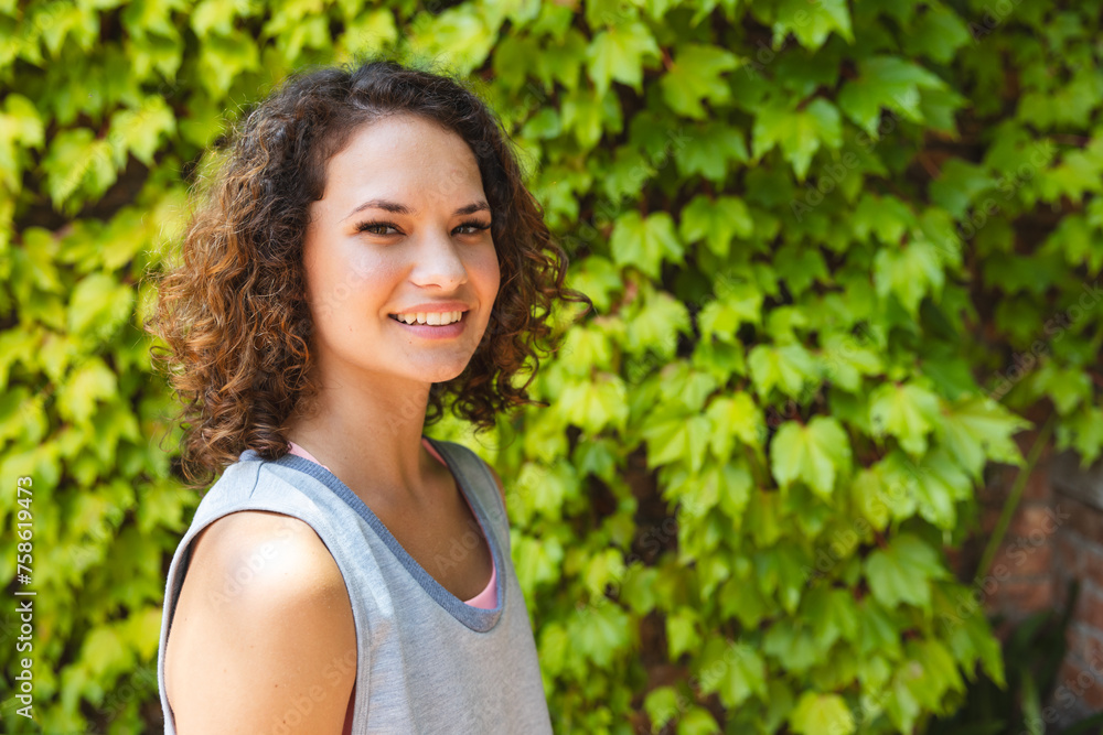 A young Caucasian woman smiles outdoors, green foliage background with copy space A young Caucasian woman smiles outdoors, green foliage background with copy space