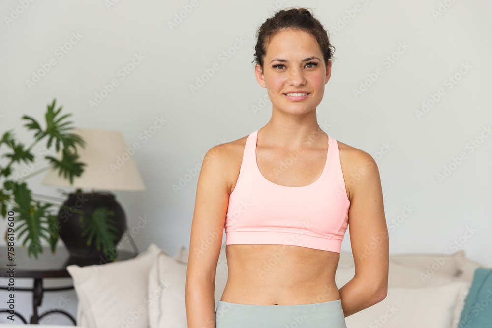 A fit young Caucasian woman stands confidently at home