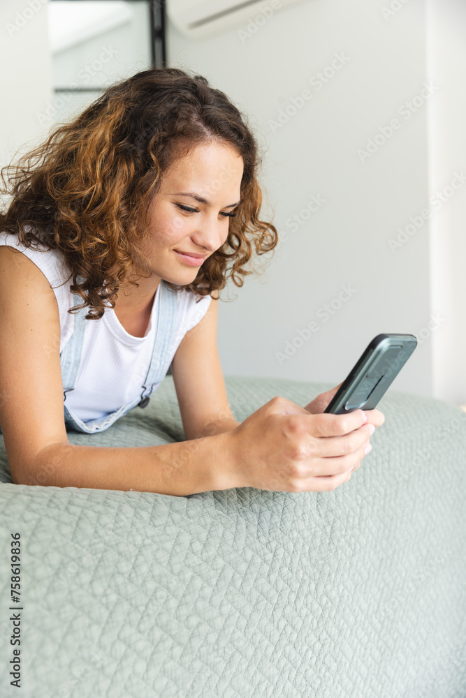 A young Caucasian woman is absorbed in her smartphone on bed at home A young Caucasian woman is absorbed in her smartphone on bed at home