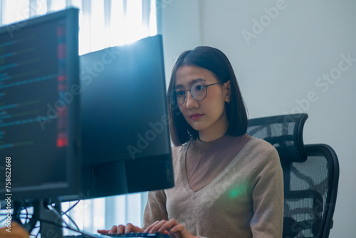 Asian prompt engineer developer coding app with software data sitting in front of computer monitor at office