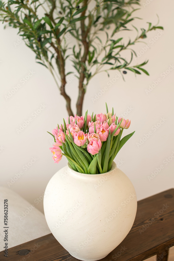 Obraz premium Pink tulips in white vase on wooden table.