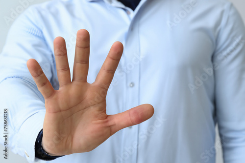 Businessman showing stop gesture on light background, closeup of hand