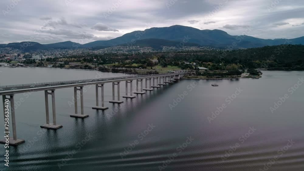 Backward shot of bridge standing still on a river with range of mountains at background. Drone view. Backward shot of bridge standing still on a river with range of mountains at background. Drone view.