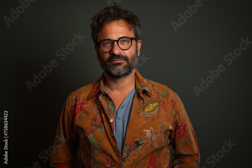 Handsome Indian man with glasses and a floral shirt against a dark background